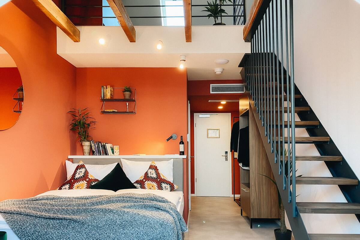 Une chambre d’hôtel moderne équipée d’un lit, d’une table de chevet, d’une bibliothèque et d’un escalier.