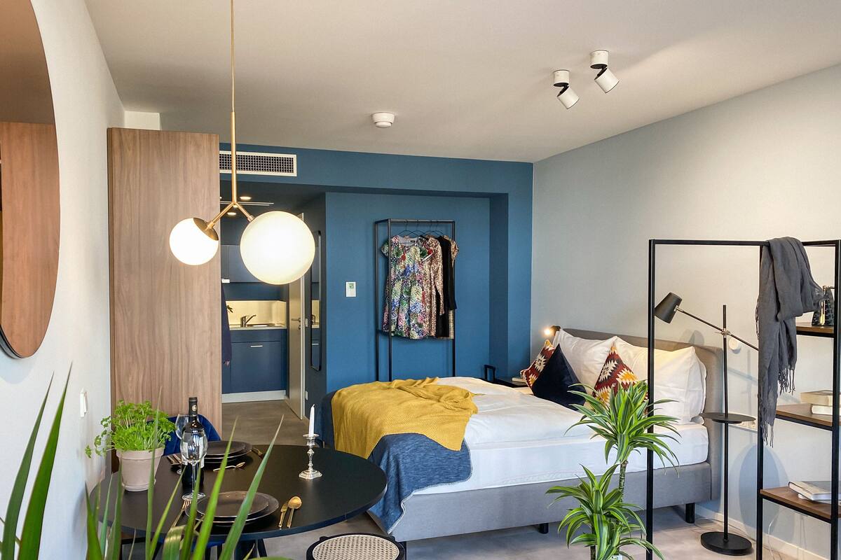 Une chambre à coucher moderne avec un lit, des tables de chevet, un bureau et un luminaire suspendu.
