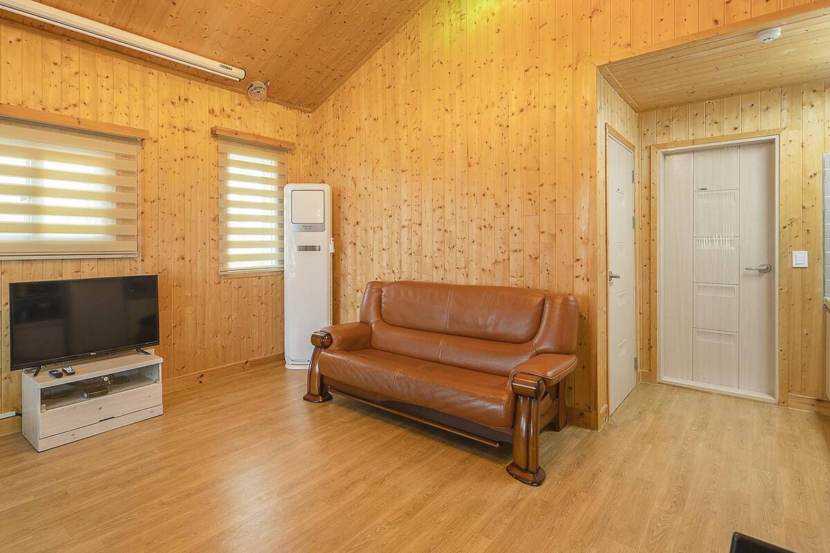 A wooden-paneled room with a leather sofa, a TV, and a white cabinet.