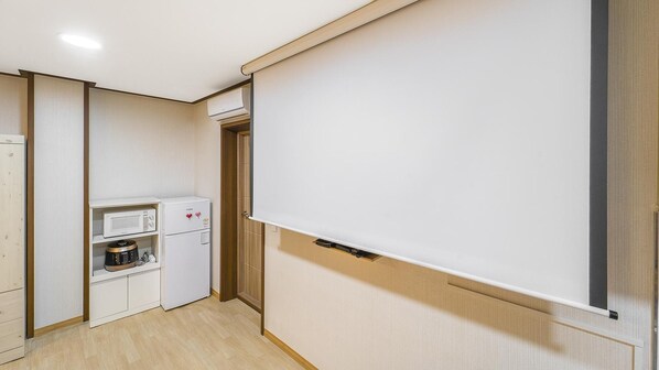 Cocina compacta con microondas, un refrigerador pequeño y un mueble de madera.