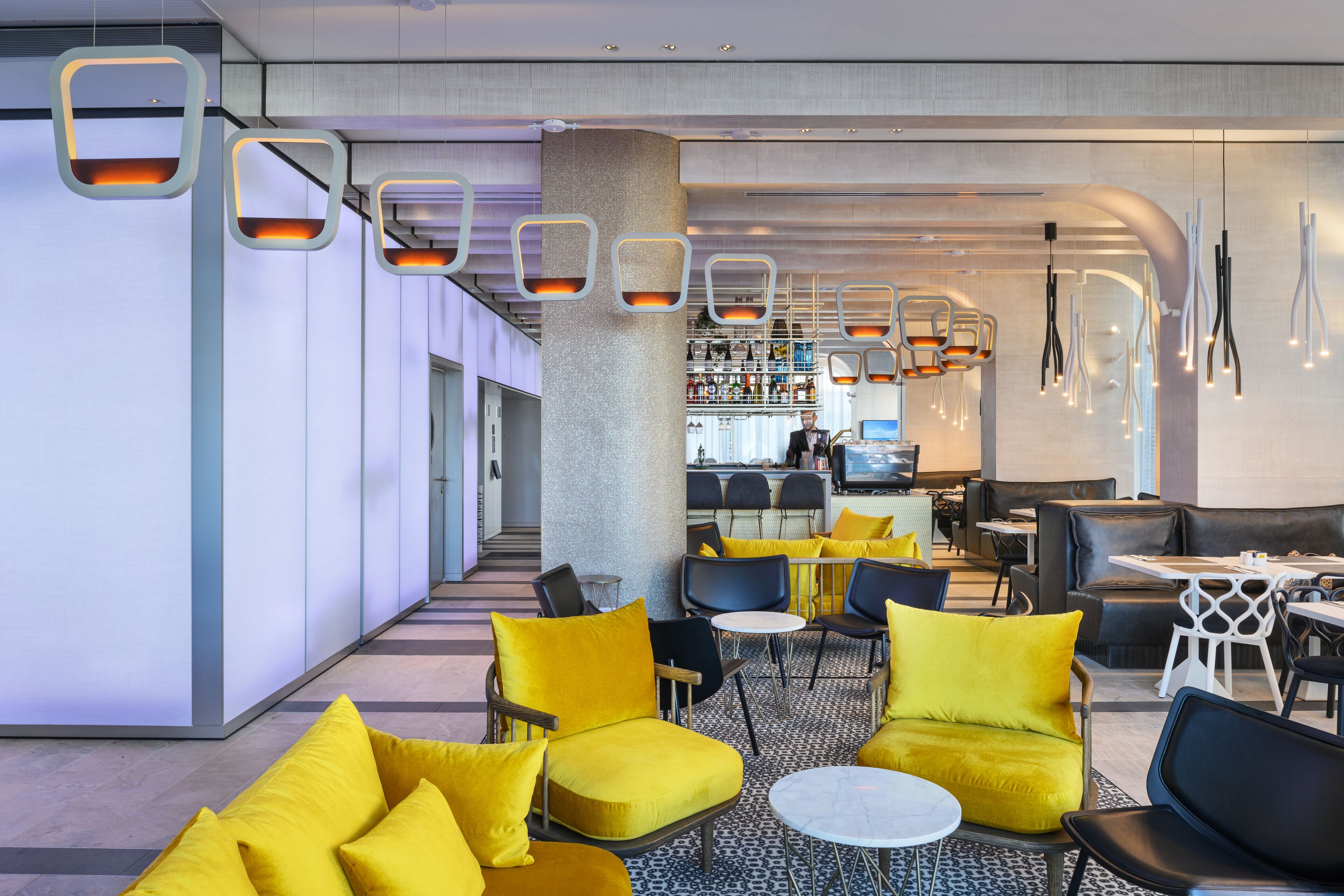 A modern interior with yellow seating, a bar area, and a patterned floor.