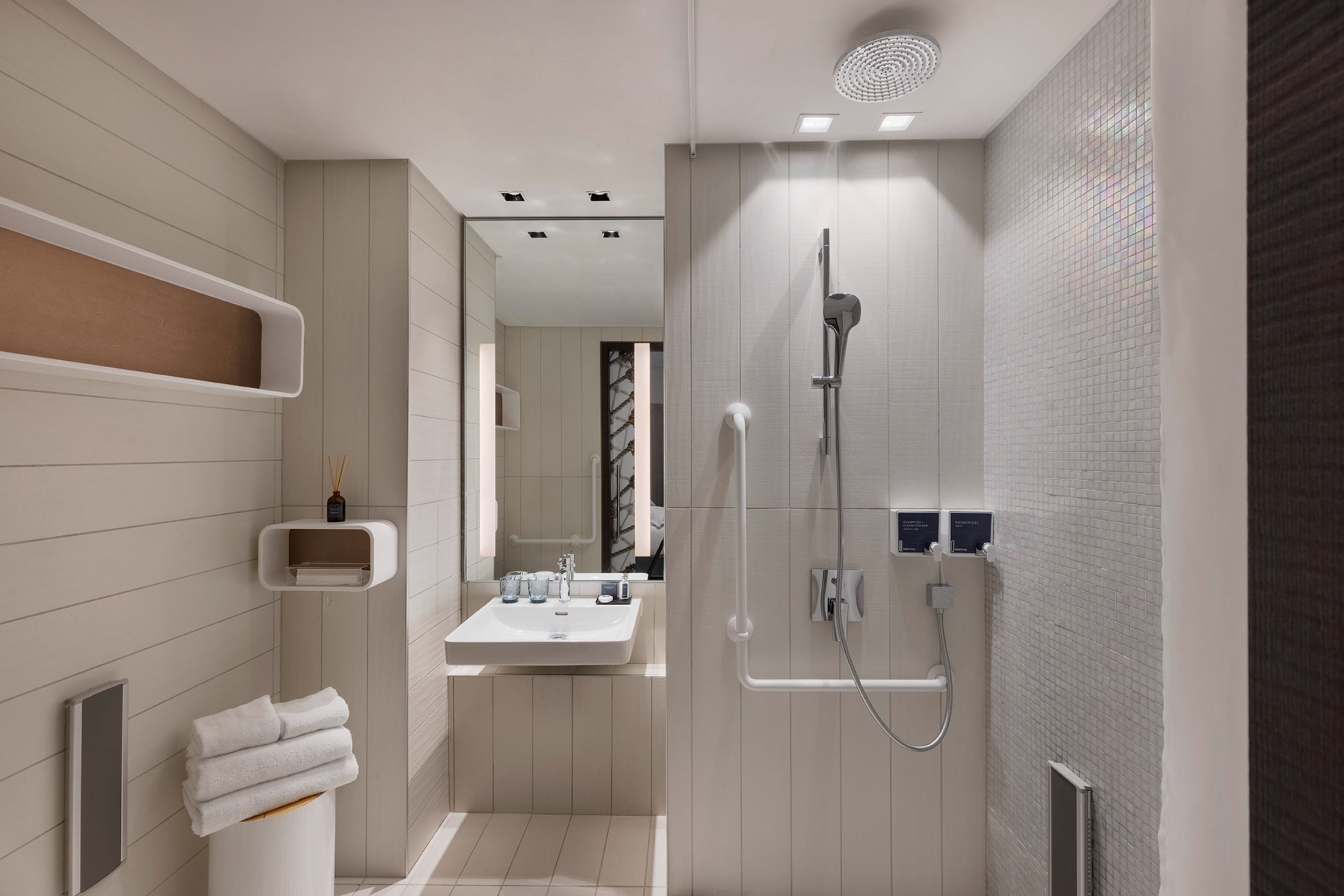 A modern bathroom with a shower, sink, and towel rack.
