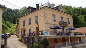 A two-story building with a balcony, signage for 'Studios du Parc', and a parking area in front. -  Sarl Aux Studios Du Parc (Le Val-d'Ajol)