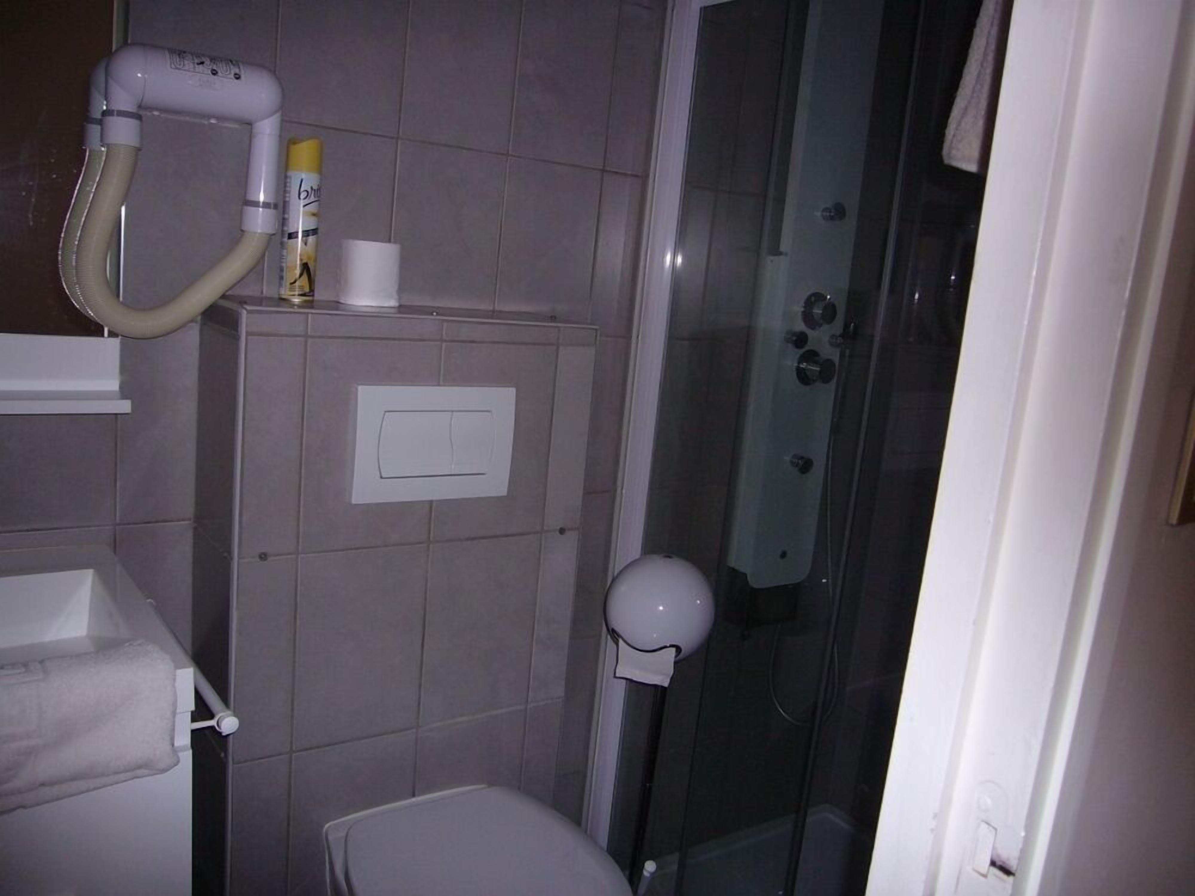 A bathroom with a toilet, a shower, and a towel rack.