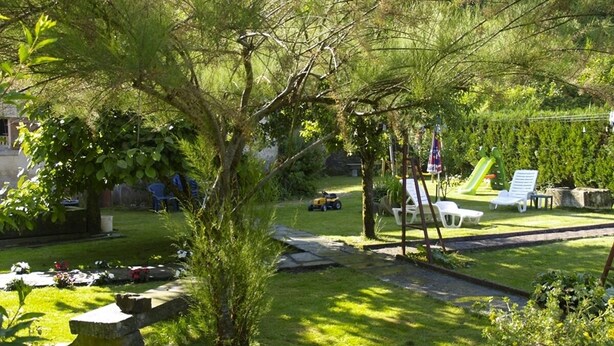 A backyard with a lawn, a swing set, and a small garden area. -  Sarl Aux Studios Du Parc (Le Val-d'Ajol)