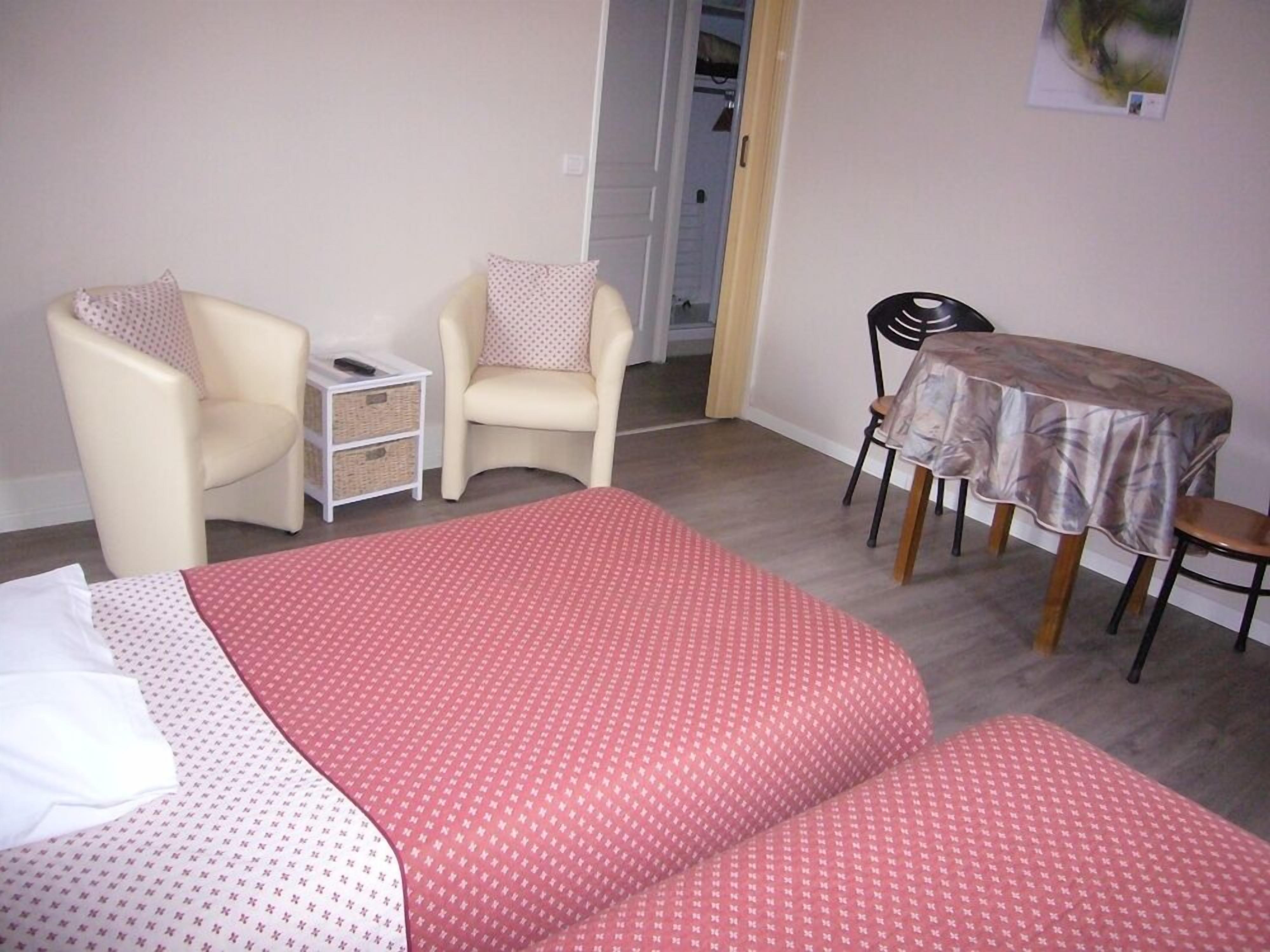 Un dormitorio con una cama, dos sillas, una mesa y una mesita de noche.