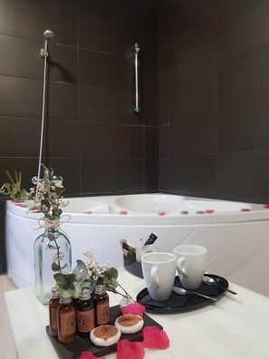 A bathroom with a bathtub, a glass vase with flowers, and toiletries on a tray. - Hotel Monasterio de Tejeda (Garaballa)