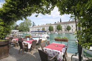Dine with a view of a historic building across the water, surrounded by lush greenery and serene river views.
