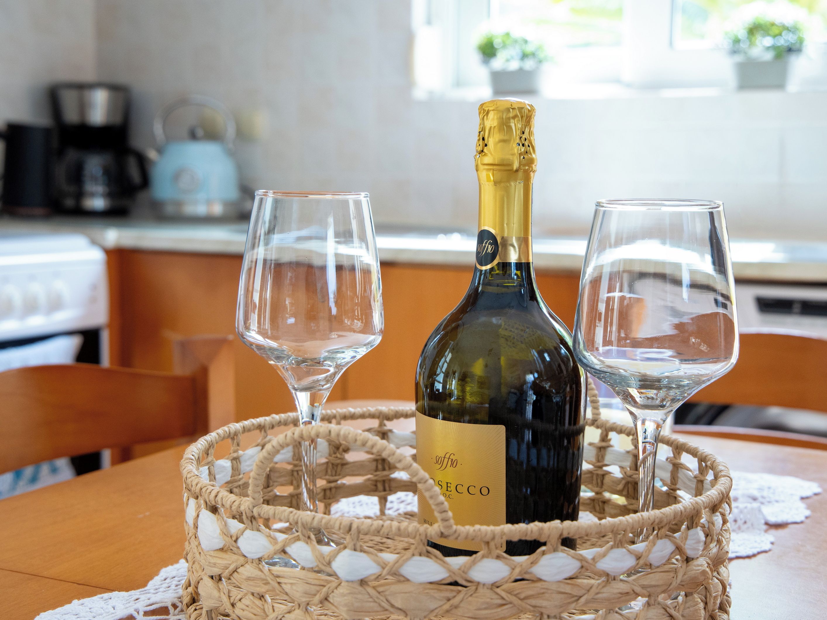 A bottle of wine and two glasses on a woven basket.