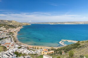 A coastal town with buildings along the shoreline, a pier, and a clear view of the sea. - Mili's House SeaView - Kalyves (Apokoronas)