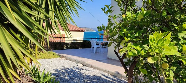 A patio area with a white chair, a small table, and a view of the sea. - Mili's House SeaView - Kalyves (Apokoronas)