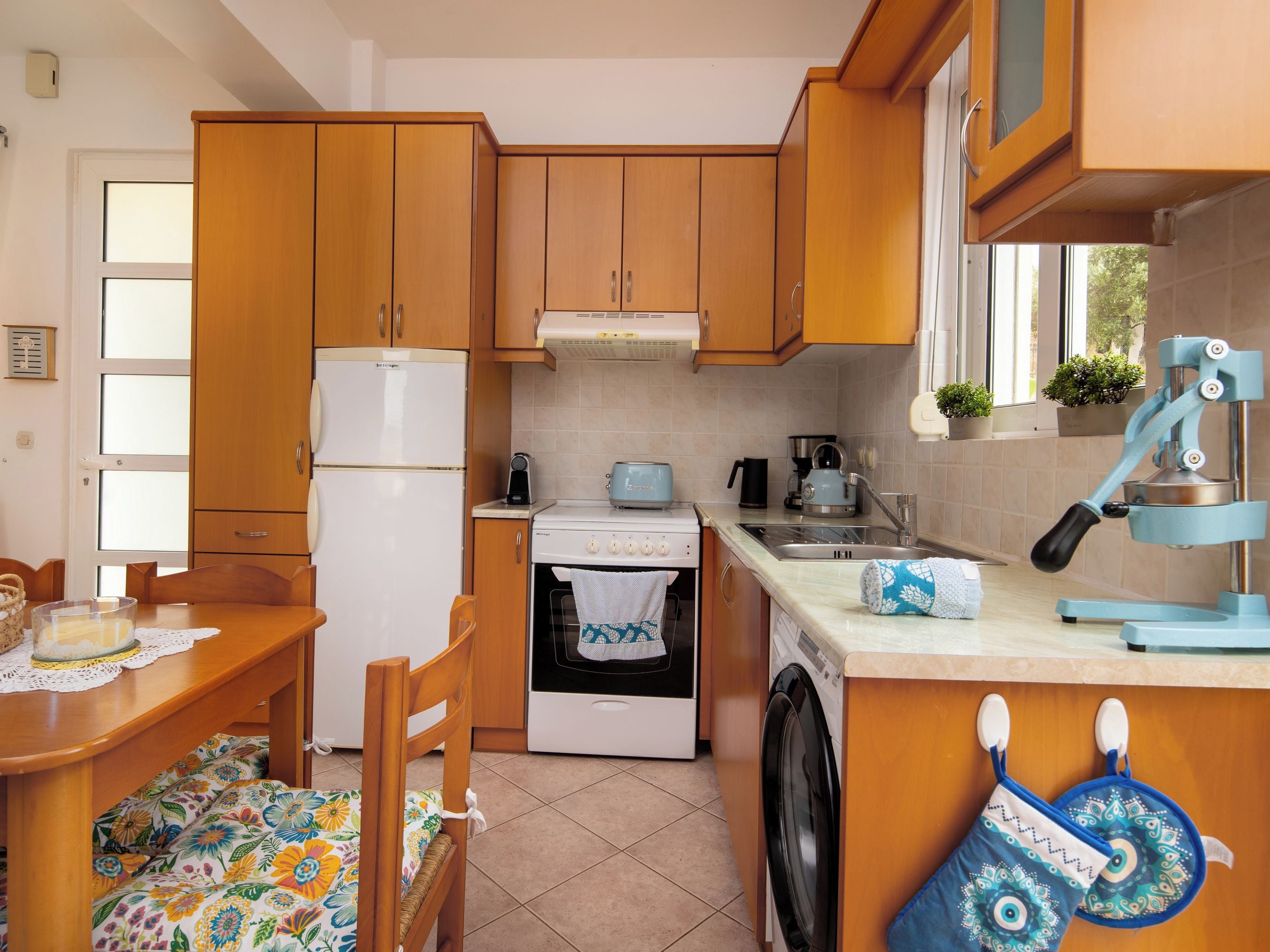 Une cuisine compacte avec des meubles en bois, un réfrigérateur blanc, une cuisinière, un lave-linge et un évier.
