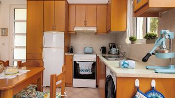 Une cuisine compacte avec des meubles en bois, un réfrigérateur blanc, une cuisinière, un lave-linge et un évier.