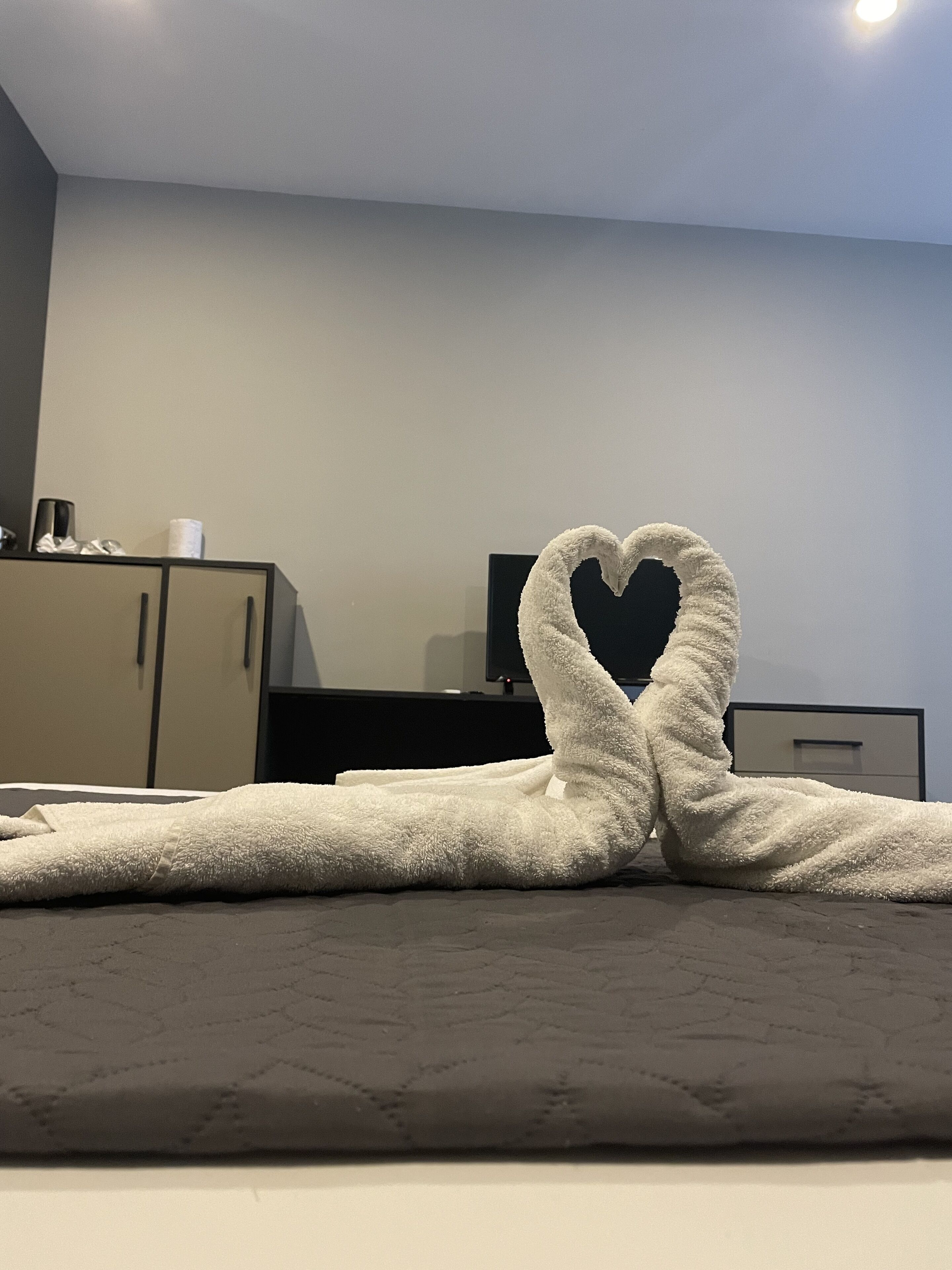 Un lit avec une serviette disposée en forme de cœur.