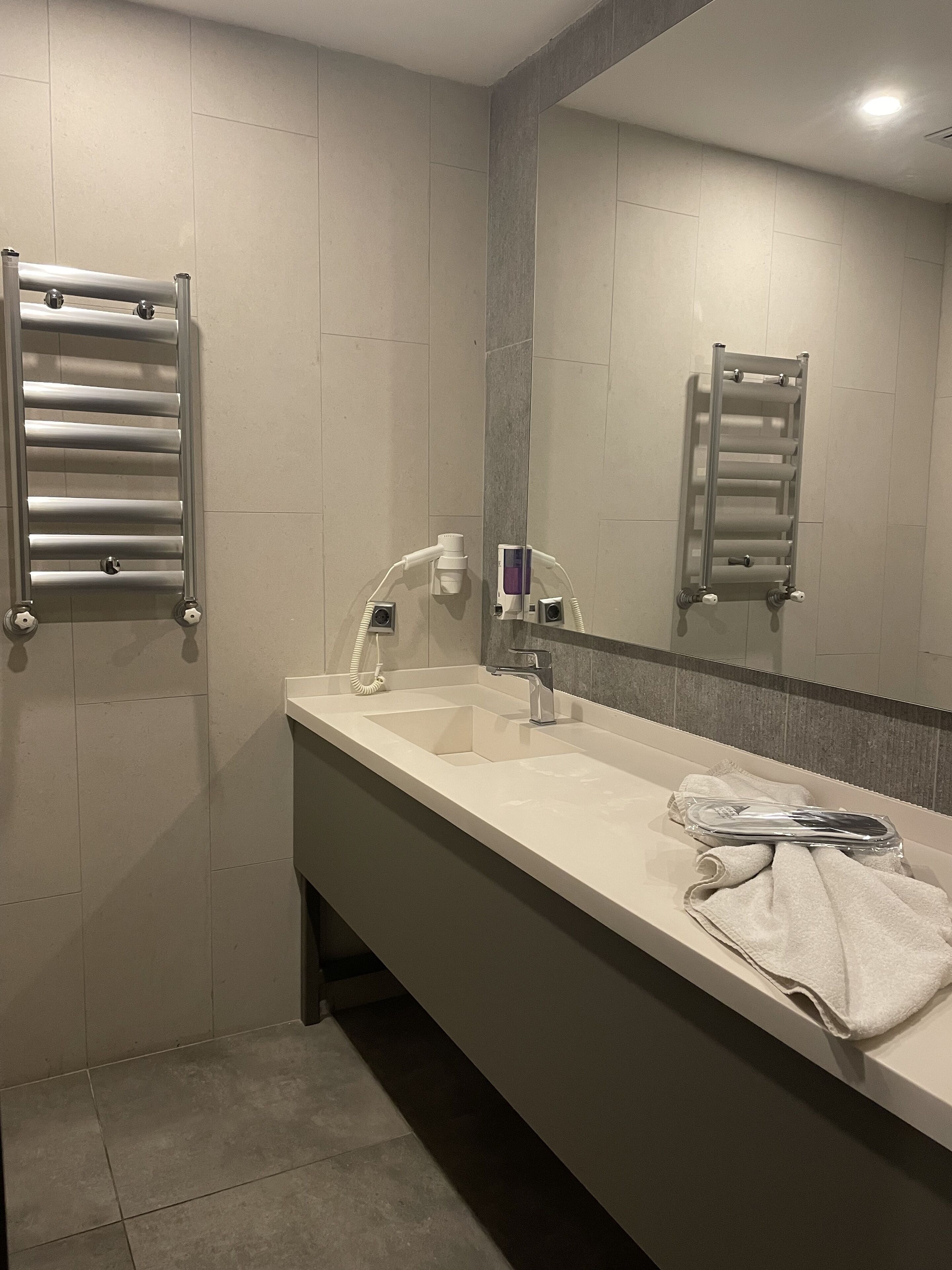 A modern bathroom with a large mirror, a sink, and a towel rack.