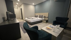 Camera d'albergo moderna con un letto, una scrivania e una sedia. È presente un tavolino con un piatto e un bicchiere.