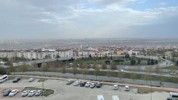 A parking lot with various vehicles, including cars and vans, and a bridge in the background.