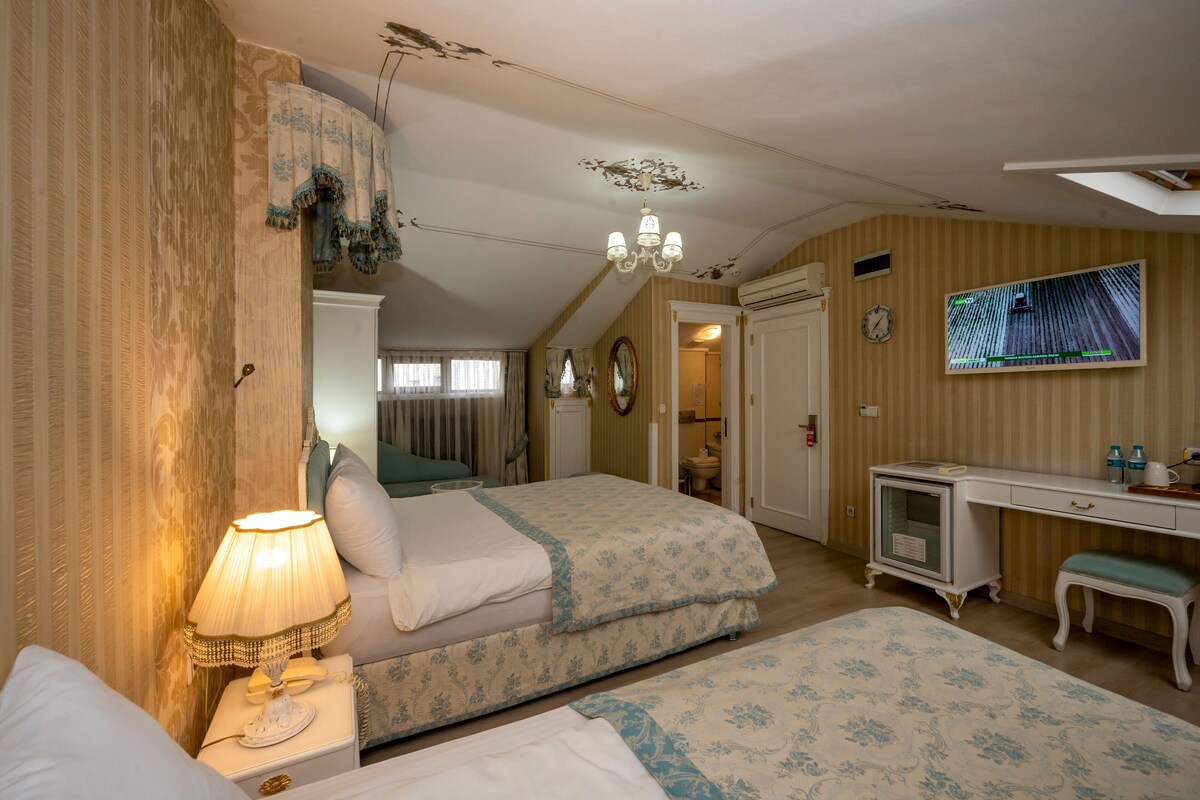A bedroom with two beds, a desk, a vanity, and a television.