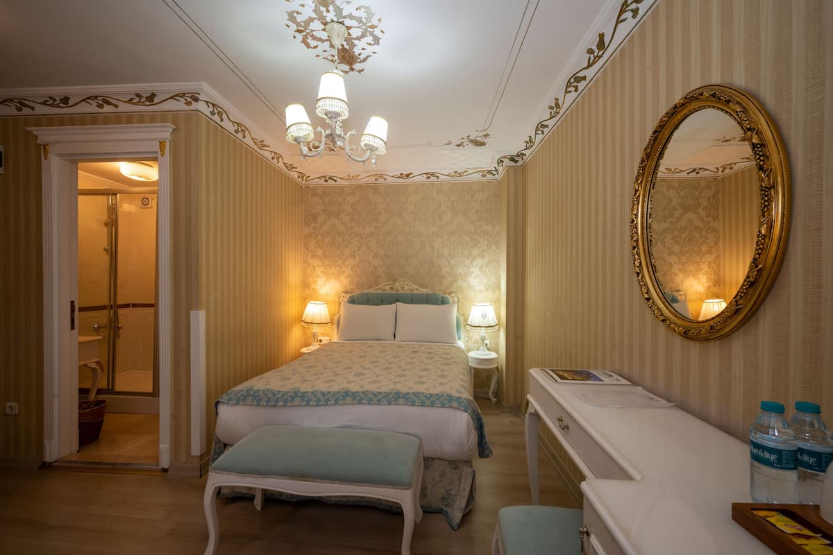 Une chambre d’hôtel comprenant un lit, des lampes de chevet, une coiffeuse avec un miroir et un bureau avec une chaise.