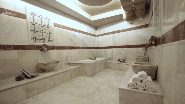 A bathroom with a bathtub, a sink, and a toilet. There are towels stacked on a shelf. - Villa Paradiso & Spa Hotel (Istanbul)