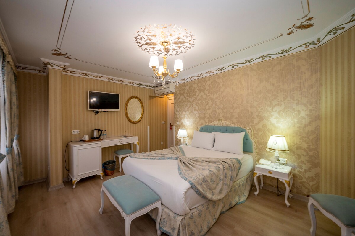 A hotel room with a bed, bedside tables, a television, and a desk with a chair.