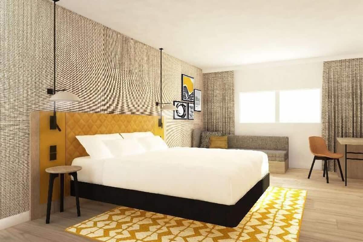 A modern bedroom with a bed, bedside tables, a desk, and a chair.