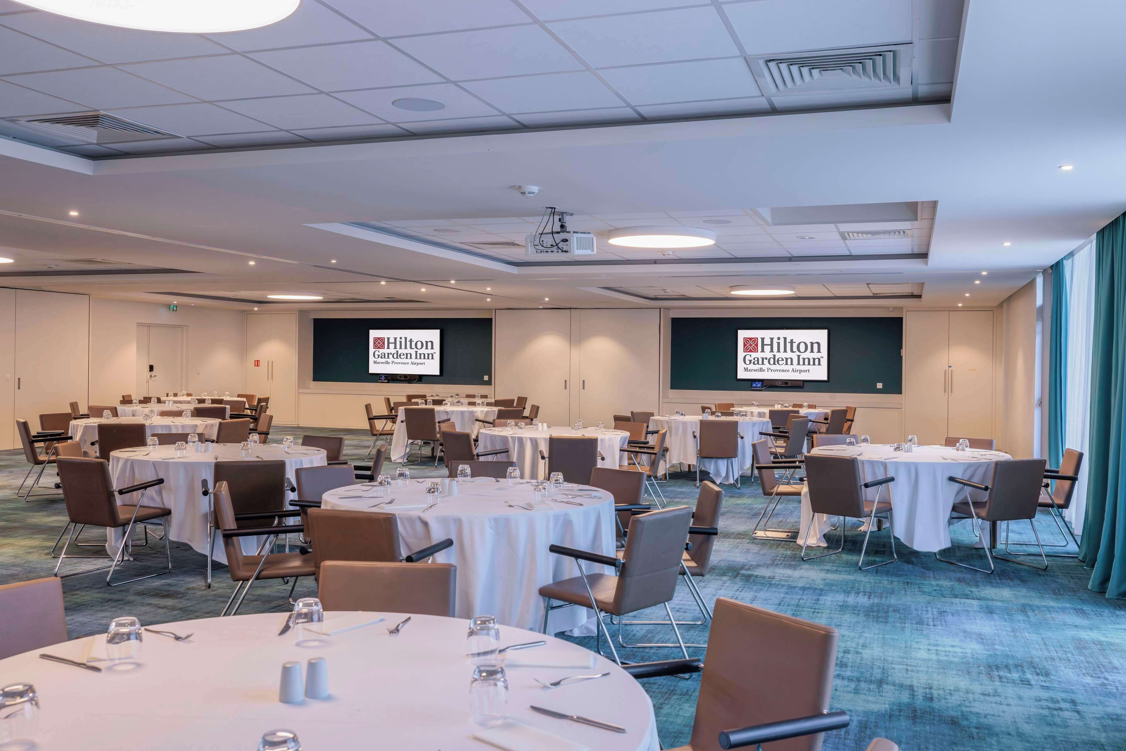 A conference room with multiple round tables, each set with chairs and water glasses.