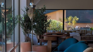 Uma área de estar moderna com assentos confortáveis, uma janela grande e um lustre pendente.
