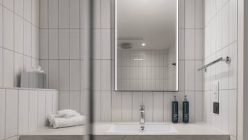 A modern bathroom with a large mirror, a sink, and two bottles of Craybreeze.