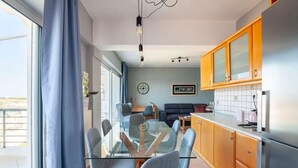 A modern kitchen with wooden cabinets and a glass dining table. - Valeria Sea View Apartment in Rethymno, Crete (Rethymno)