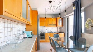 A modern kitchen with wooden cabinets, a glass dining table, and a built-in oven. - Valeria Sea View Apartment in Rethymno, Crete (Rethymno)