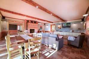 A spacious living area with a dining table, chairs, a sofa, and a fireplace.