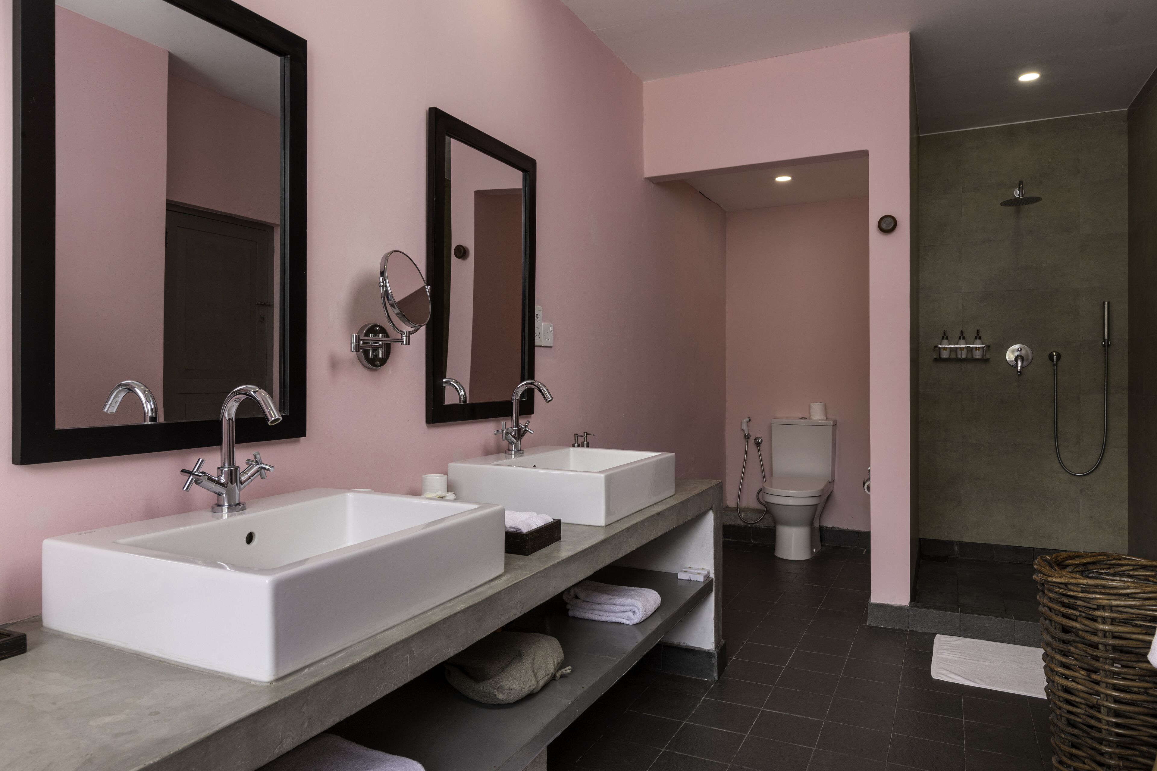 A modern bathroom with two white sinks, a large mirror, and a shower area.