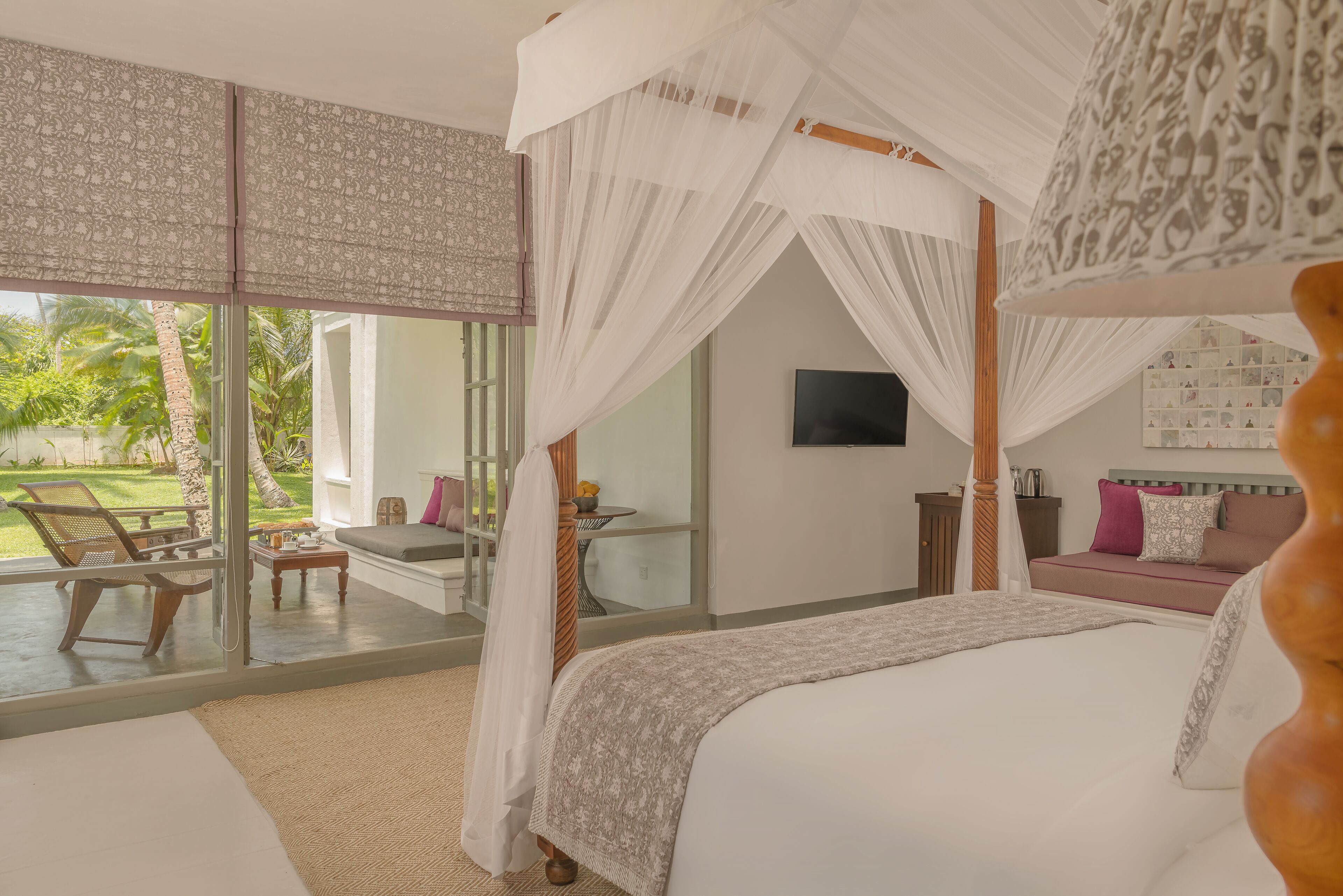 Un dormitorio con una cama grande, televisión, balcón con una silla y vistas al exterior.