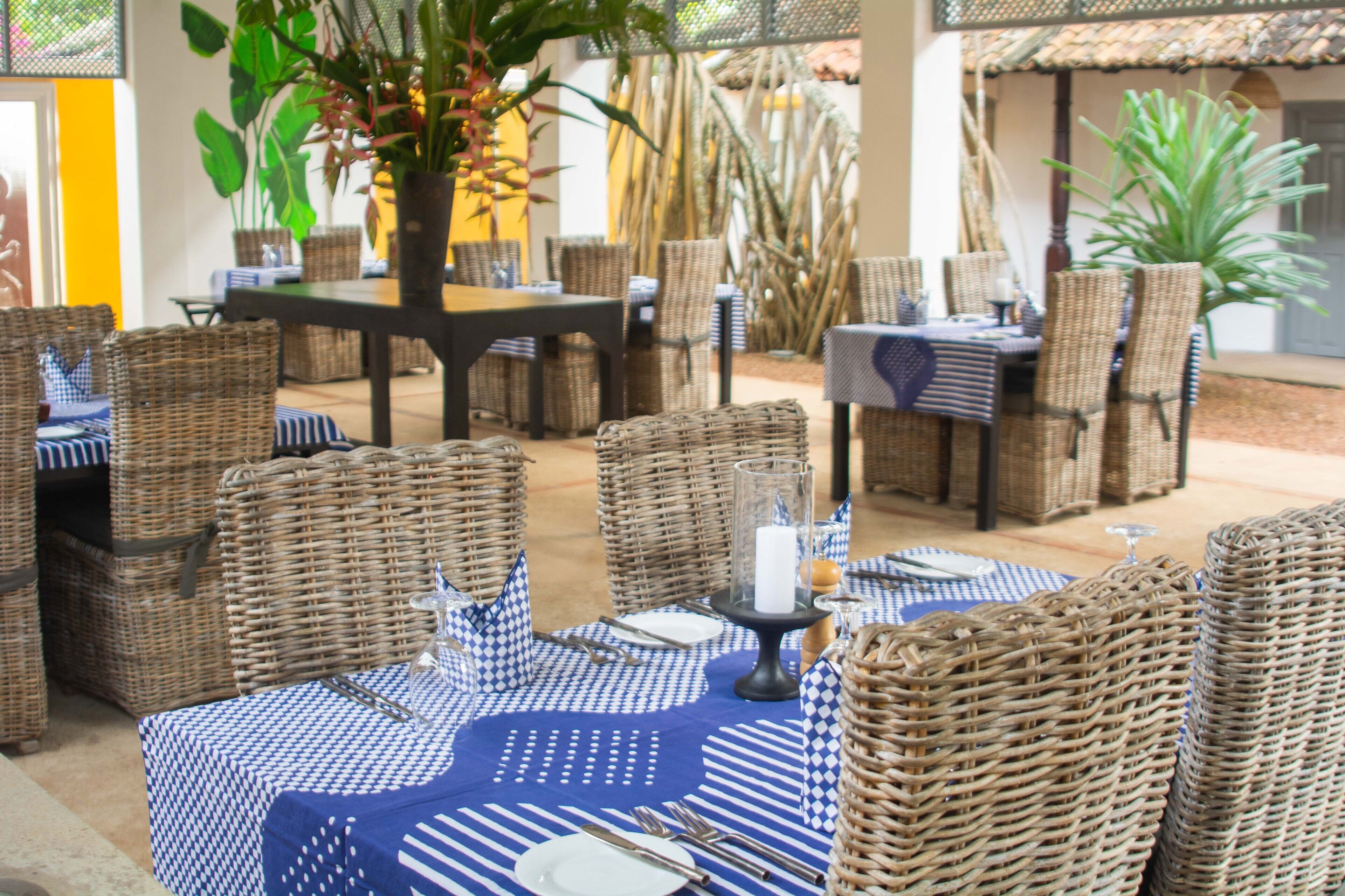 Un ristorante con mobili in vimini e tovaglie bianche e azzurre a quadri.