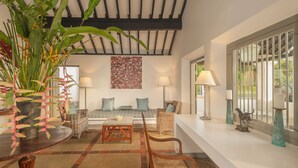 A modern living room with a sofa, two chairs, a coffee table, and a large plant. There are two lamps on either side of the sofa. - The Villa Bentota by KK Collection (Bentota)
