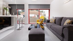 A modern living room with a grey sofa, a yellow armchair, a glass coffee table, and a flat-screen TV. -  A Luxury Retreat in Corfu Town by Konnect, Two-Bedroom Apartment (Corfu)