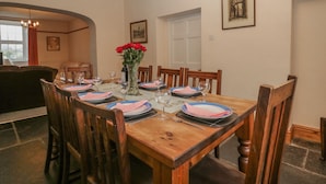 Une salle à manger avec une table en bois dressée pour six personnes, entourée de chaises en bois.