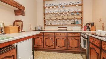 Una cocina con armarios de madera, encimera, estufa, lavabo y una repisa con vajilla.
