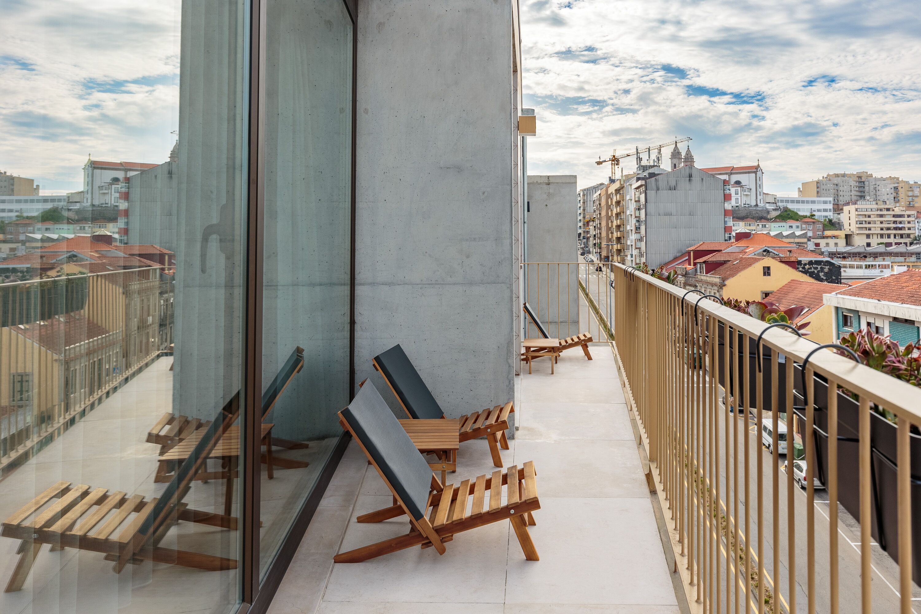 A balcony with wooden lounge chairs and a concrete pillar.