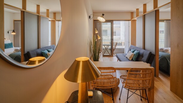A modern hotel room with a round mirror, a dining table with chairs, a sofa, and a large window with curtains. - Feel Porto Corporate Housing Campanhã (Porto)