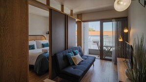 A modern hotel room with a bed, a sofa, and a balcony with a view. - Feel Porto Corporate Housing Campanhã (Porto)