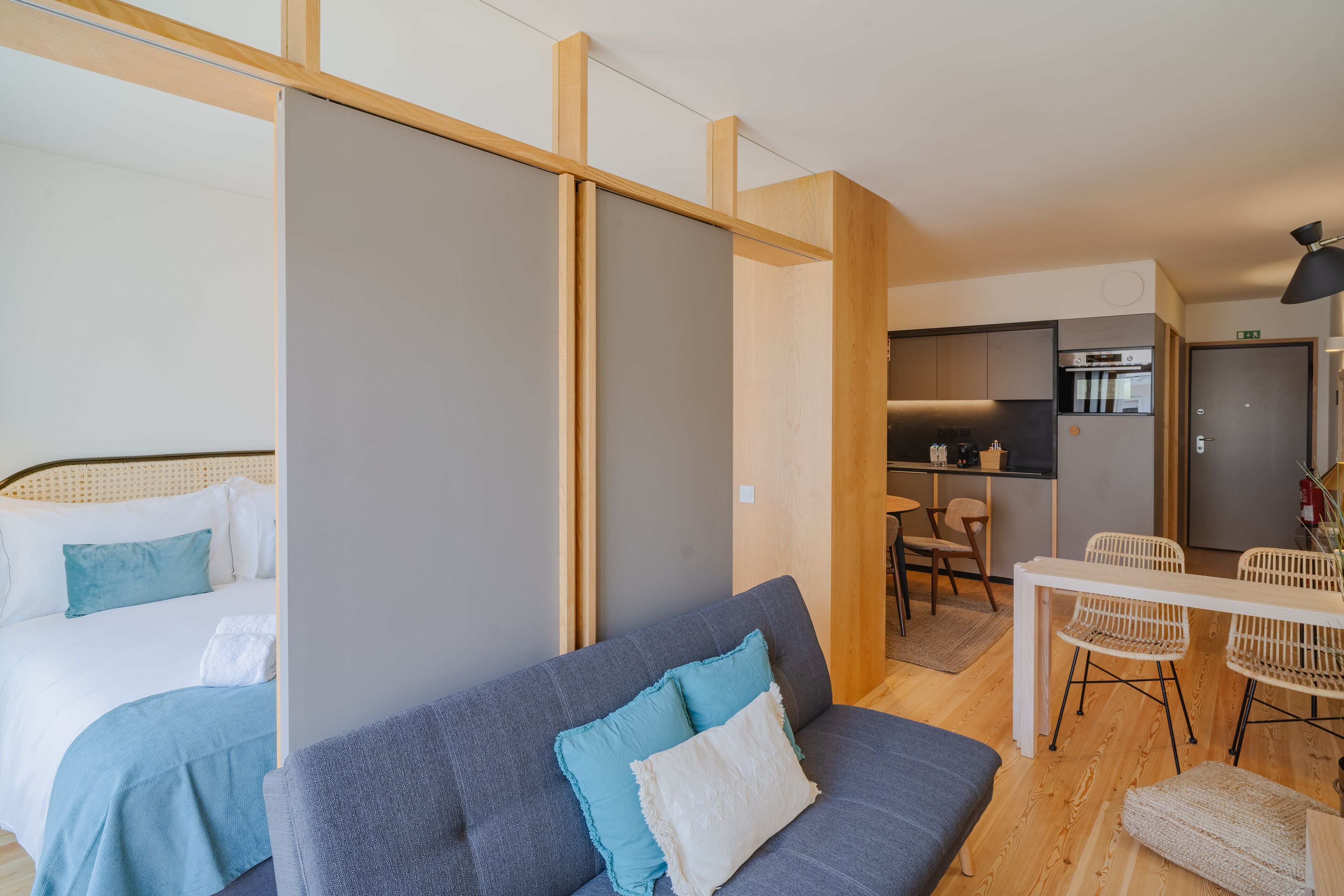 Een moderne hotelkamer met een bed, een bank, een eethoek en een keuken.