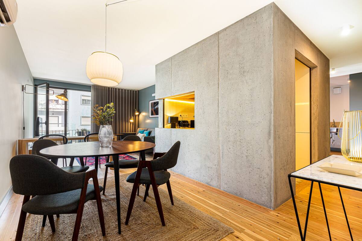 Un espace repas moderne avec une table ronde, des chaises foncées et un plancher en bois.