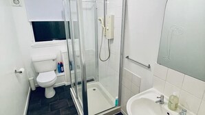 A modern bathroom with a glass-enclosed shower, a white toilet, and a pedestal sink. - Modern 2 Bedroom Apartment With Free Parking (Glasgow)