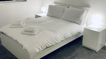 Quarto com cama, mesas de cabeceira e janela.