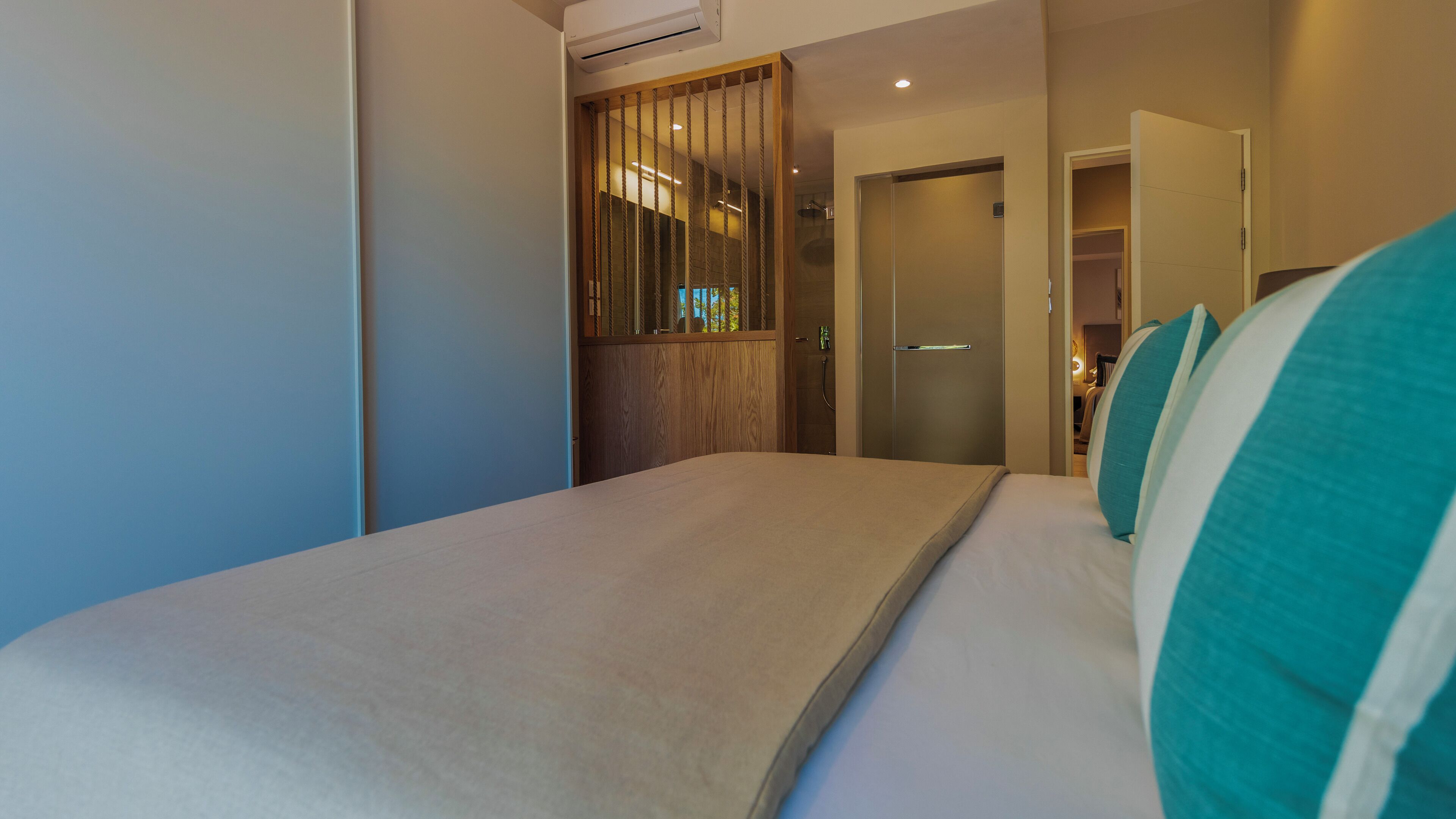A hotel room with a bed, a wooden wardrobe, and a shower area.