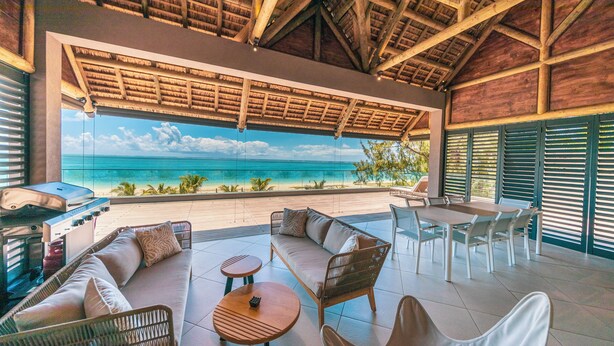 Un espace extérieur abrité, avec vue sur l’océan, comprenant un barbecue et une table à manger.