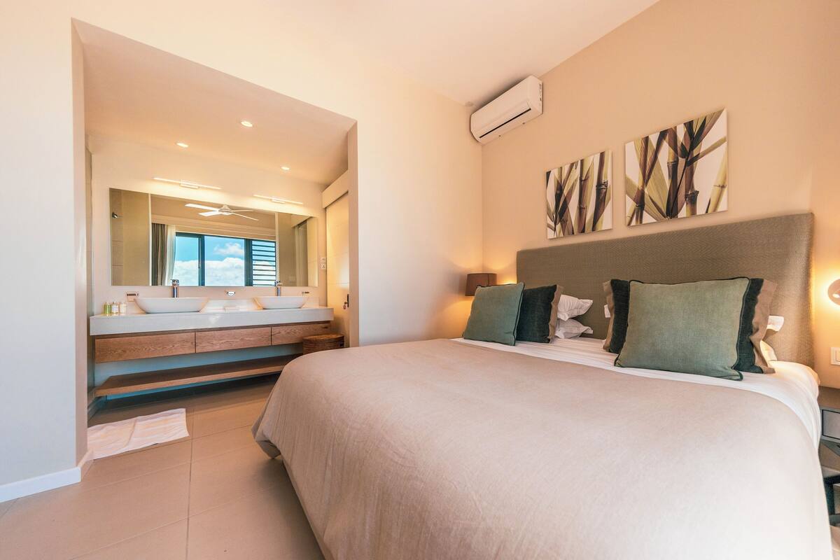 Ein modernes Schlafzimmer mit einem großen Bett, einem Schminktisch mit Spiegel und einem Deckenventilator.