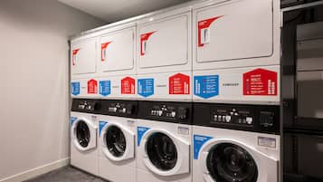A row of front-loading washing machines in a commercial laundry room.